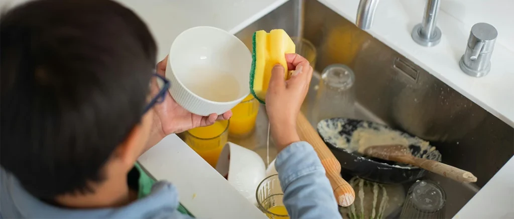 Man washing all the dishes on the sink to drain