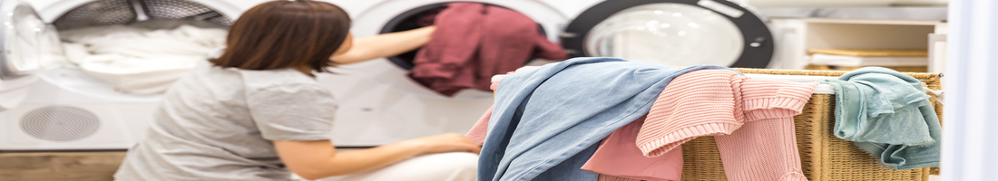 Woman Loading Dirty Clothes In Washing Machine For Washing In Utility Room