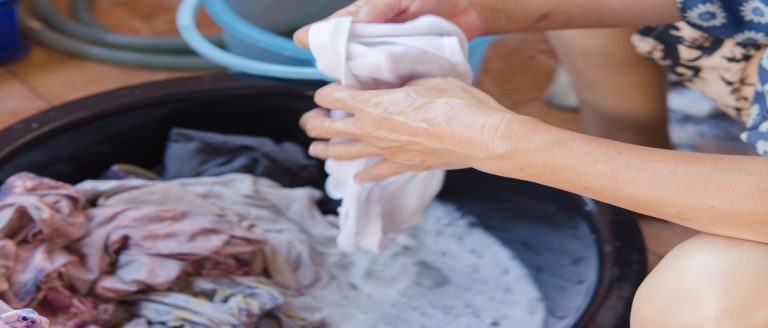 woman hands washing clothes in a plastic basin