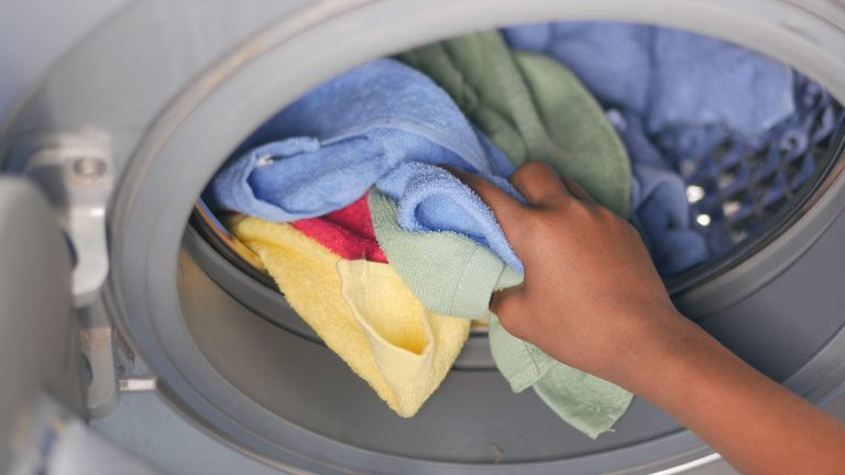 Towels being loaded into a washing machine