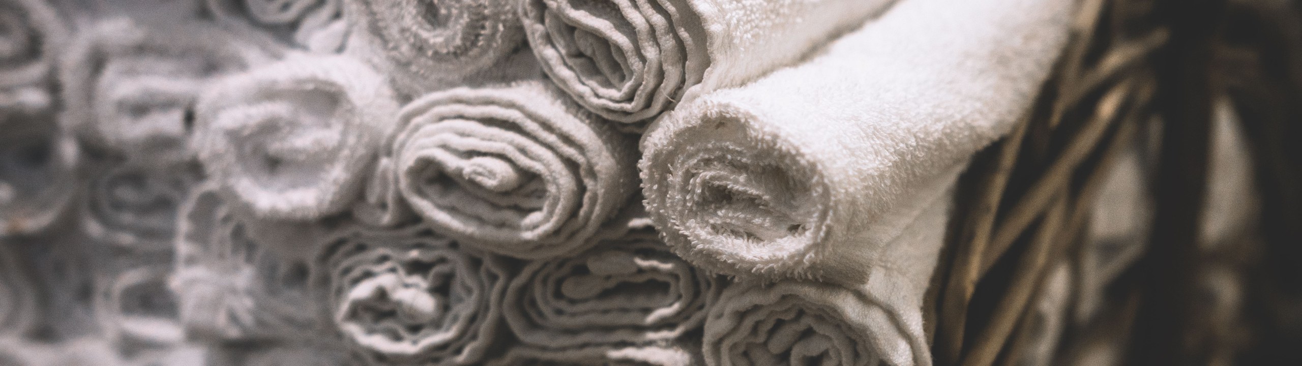 Stack of neatly rolled white towels in a woven basket