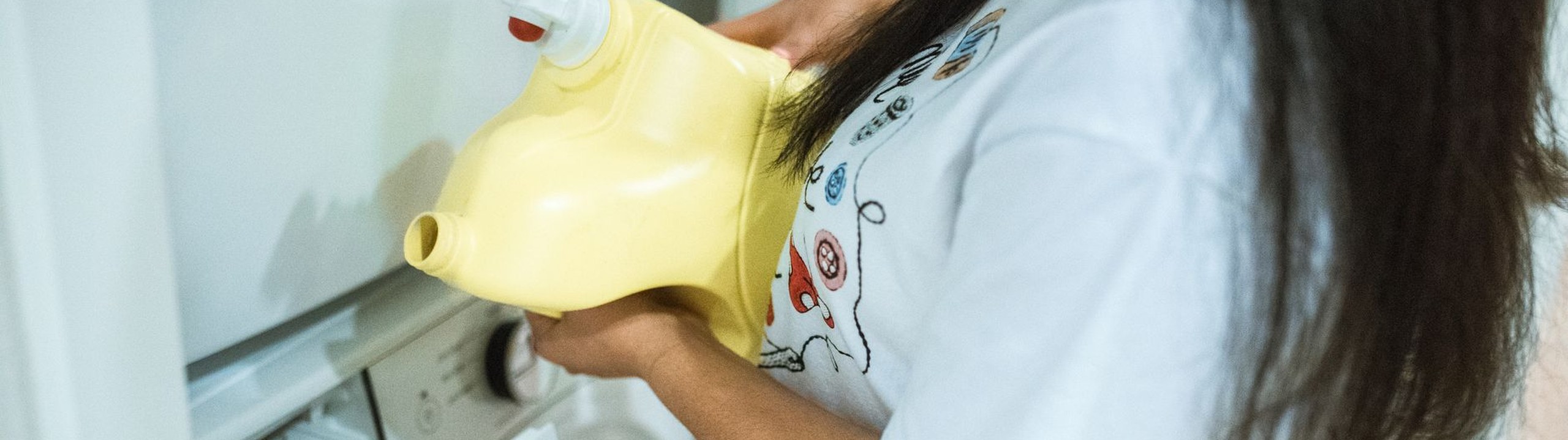 Fabric softener being poured into a washing machine drawer before a laundry cycle