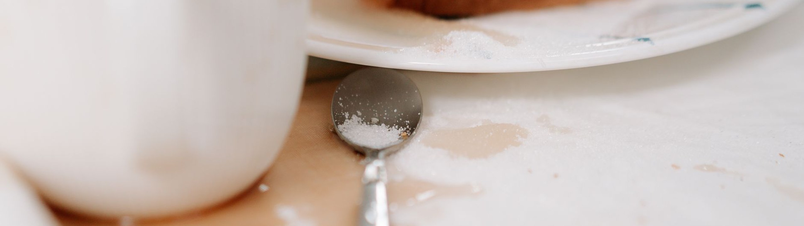 Brown liquid spill and scattered white powder on a white tablecloth, like a fresh oil stain to cover with talc or cornstarch