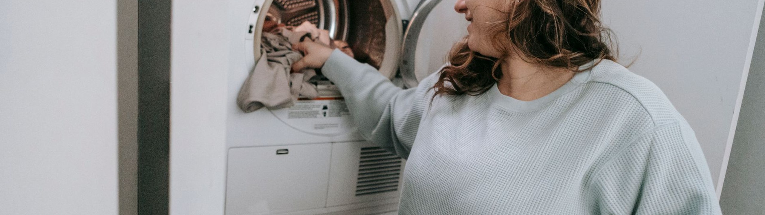 Stain-treated clothes being loaded into a washing machine to get olive oil out